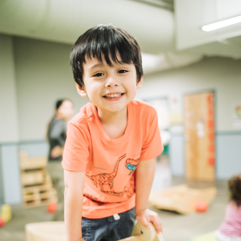 A small boy with dark hair smiling into the camera
