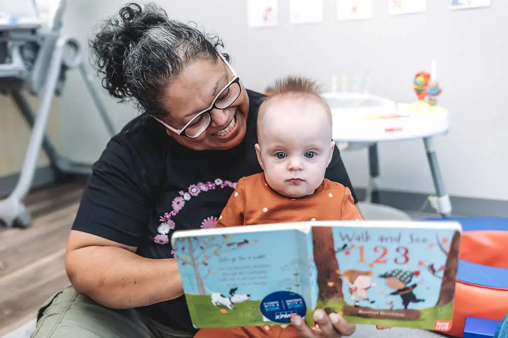 Teacher reading a book with a young child, fostering learning and connection.