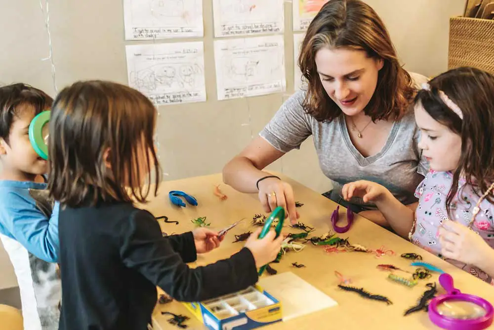 Teacher guiding young children in a teachable moment at a daycare.