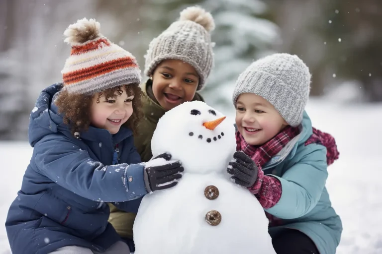 Three smiling children building a snowman in winter, wearing warm coats and hats.